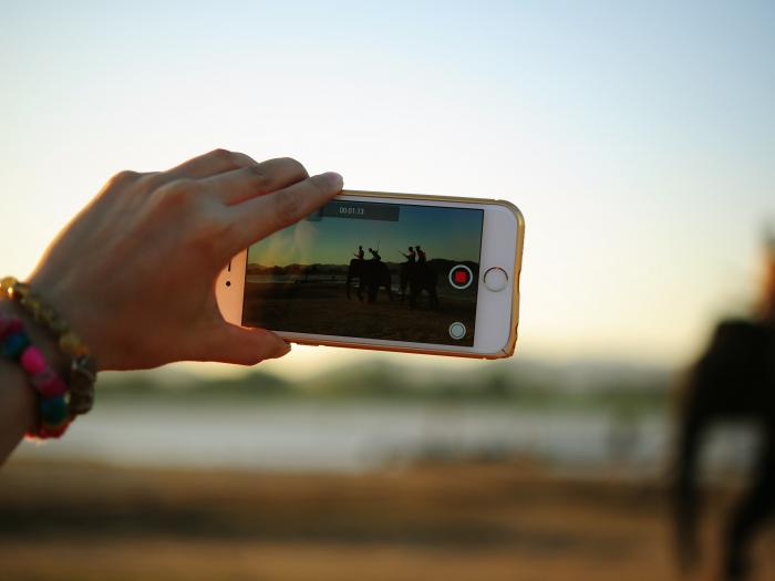 Eine Hand hält ein Smartphone zum Filmen in die Höhe